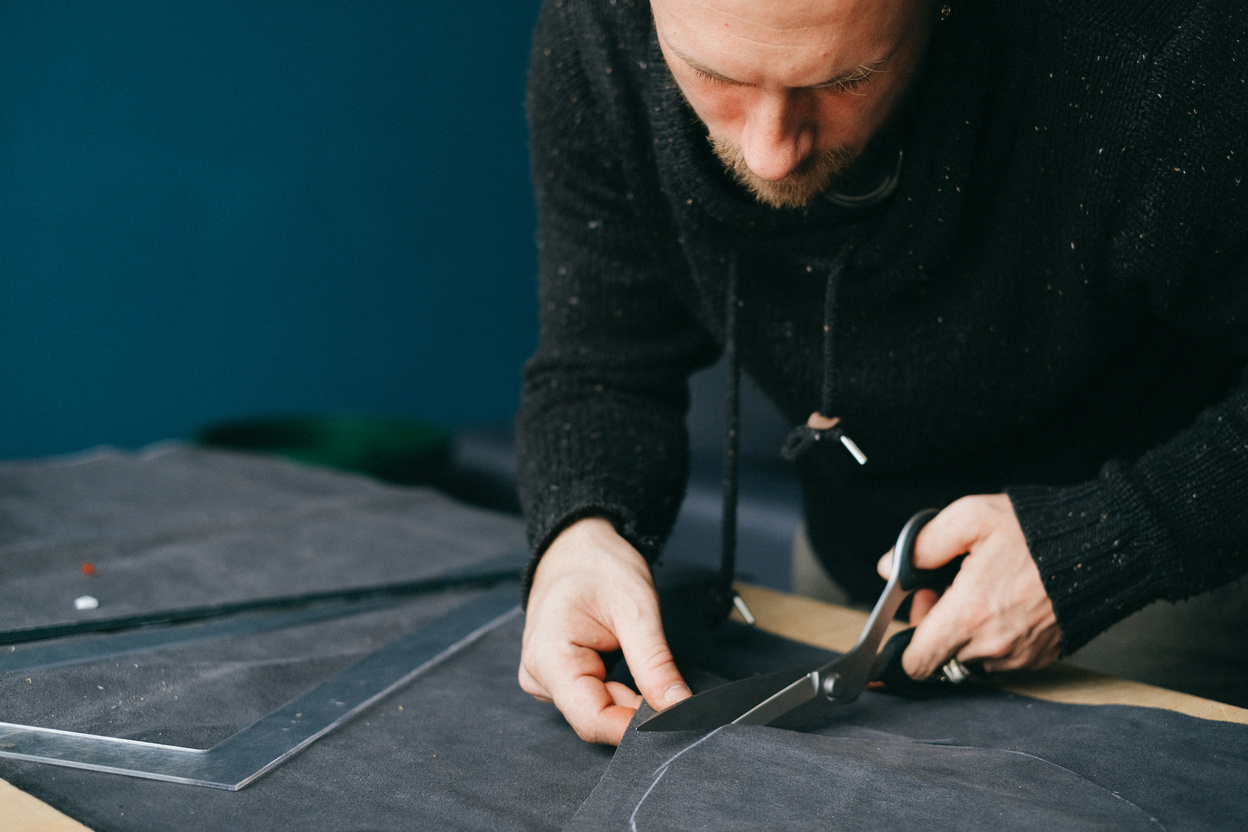 Male designer cutting piece of leather in workshop